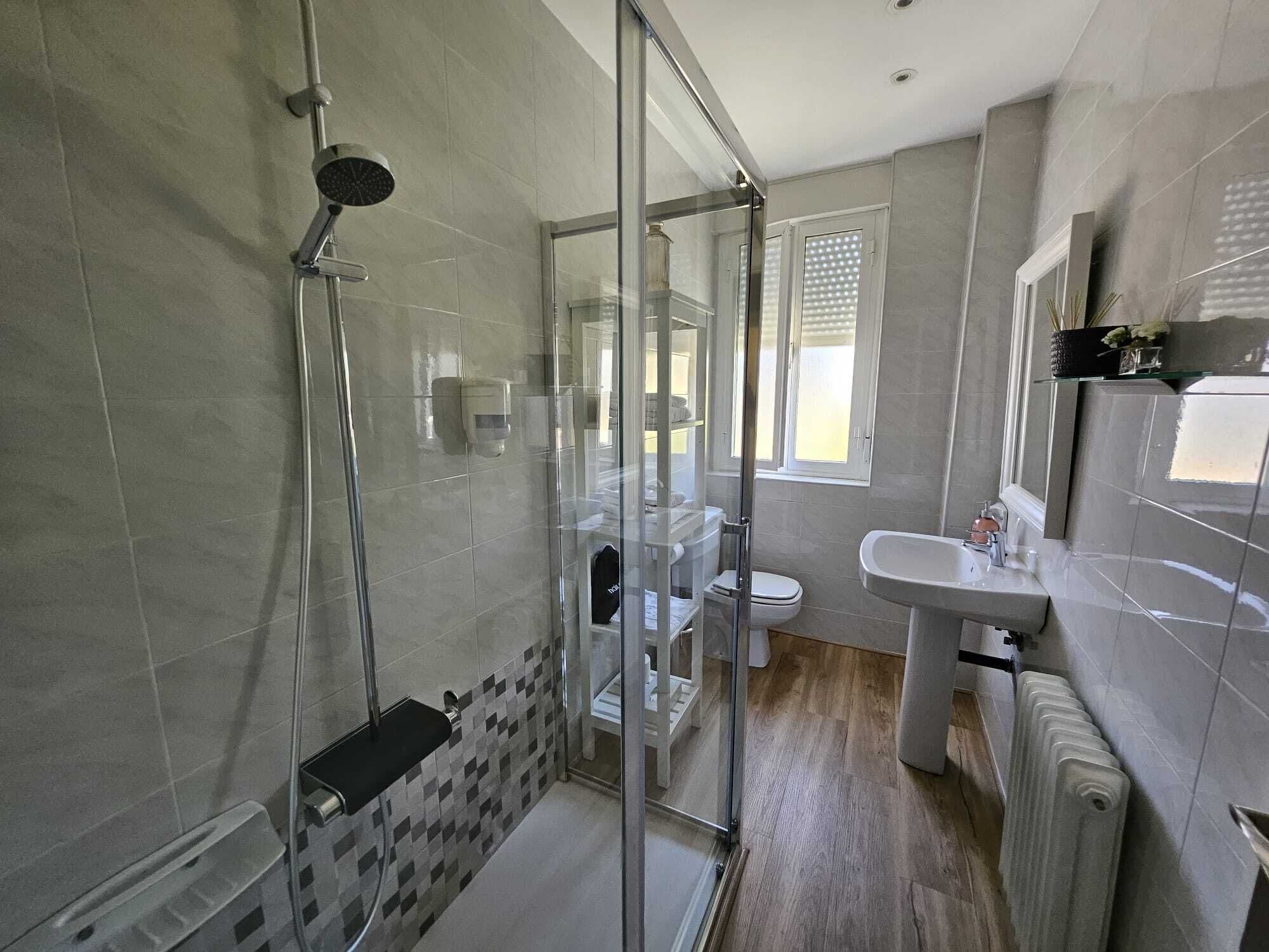Un baño moderno con cabina de ducha de vidrio, inodoro y lavabo.