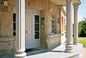 A building with a stone facade, large columns, and a door with glass panels. - Casablanca Hotel Studios (Santa Marta de Tormes)
