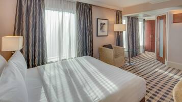 Una habitación de hotel con dos camas, una silla, una mesa de vidrio y un espejo.