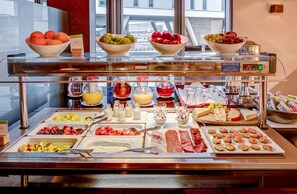 Un bufé con diversas opciones de comida, incluyendo frutas, quesos y embutidos.