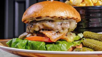 A burger with a side of fries and pickles on a plate.