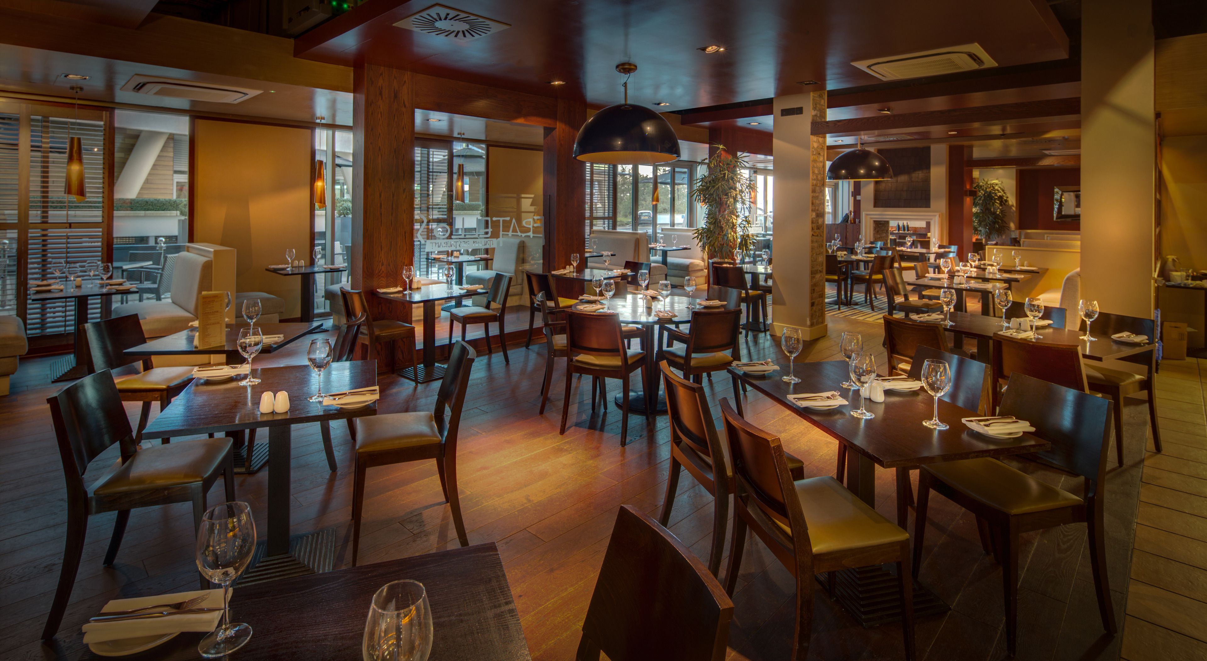 Ein geräumiges Restaurant mit mehreren Tischen und Stühlen, großen Fenstern für natürliches Licht und einem modernen Interieur.