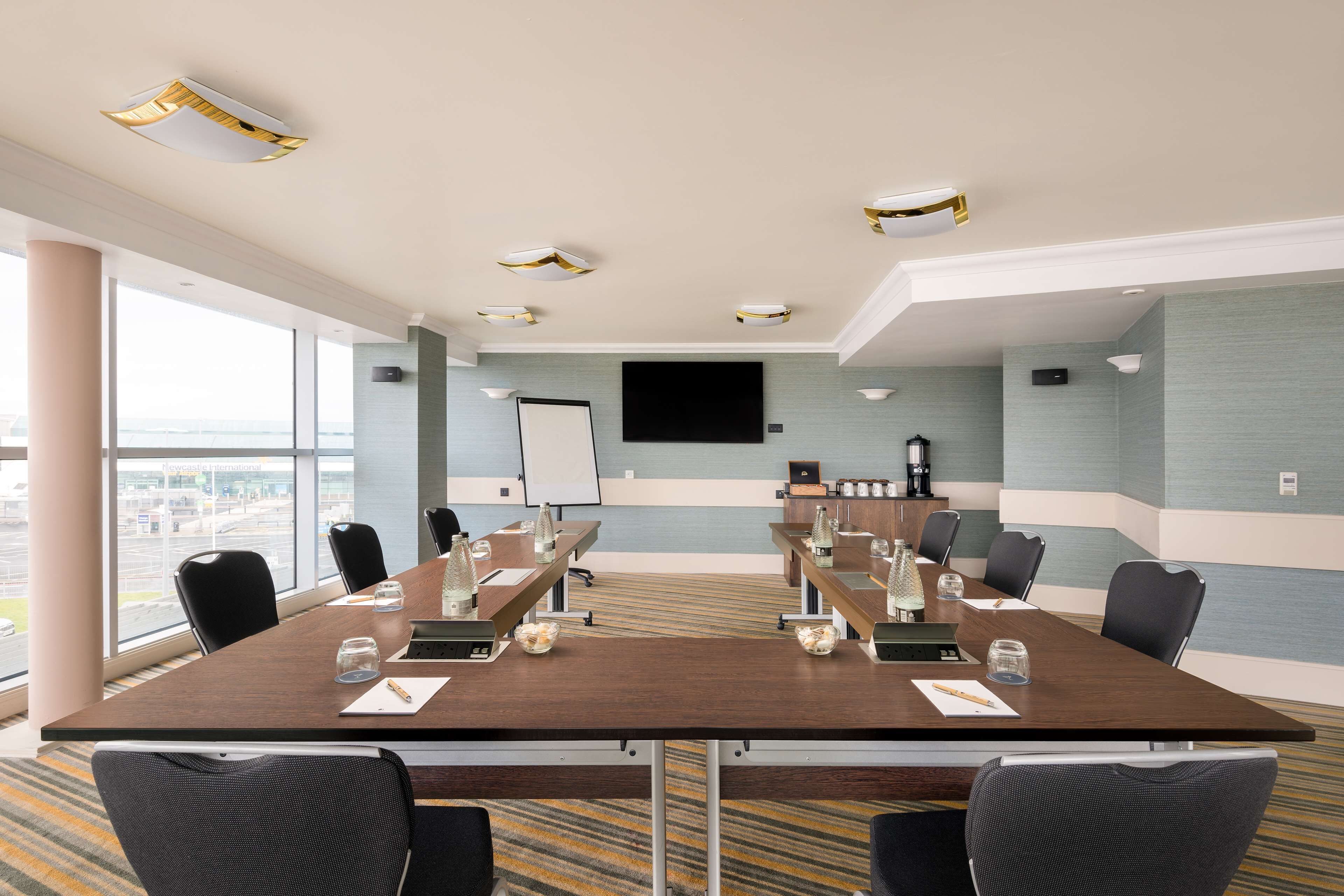 A conference room with a long table, chairs, a whiteboard, and a large window with a view.