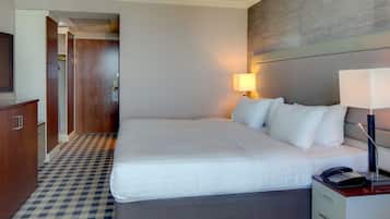 A hotel room with a large bed, bedside lamp, and a telephone on the nightstand.
