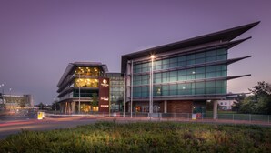 A modern hotel with a glass facade, a prominent sign for 'Doubletree by Hilton', and a well-lit entrance. - DoubleTree by Hilton Hotel Newcastle International Airport (Newcastle-upon-Tyne)