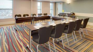 Un salón de conferencias con una larga mesa, sillas y suelo alfombrado.
