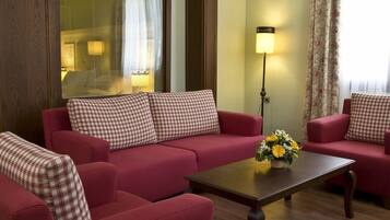 Uma sala de estar com um sofá vermelho, uma mesa de centro de madeira e um abajur.