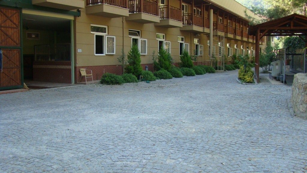 Une cour dallée de pierres, un bâtiment doté de nombreux balcons et un espace de repos abrité.