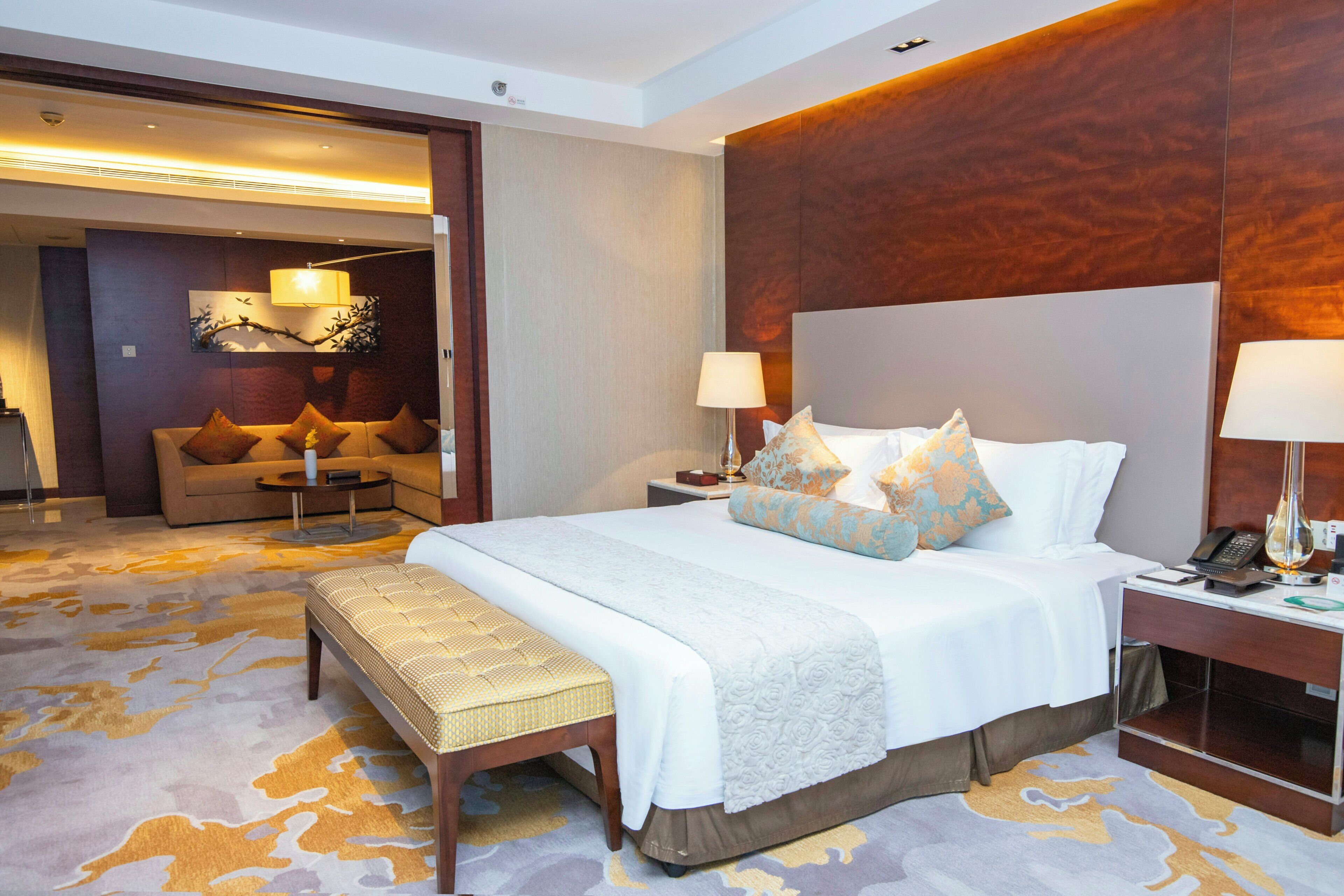 A hotel room with a large bed, bedside tables, a sofa, and a desk with a telephone.