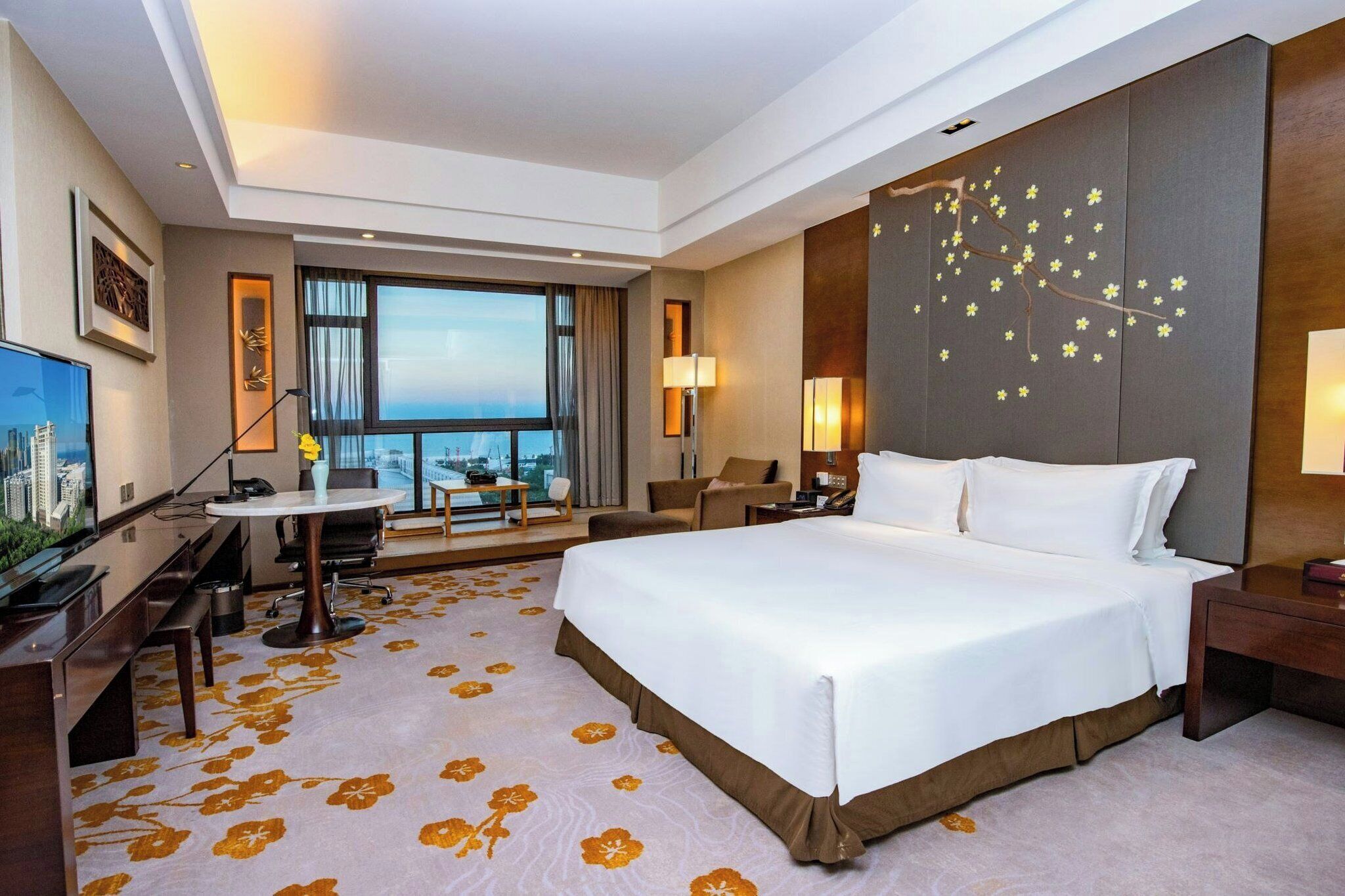 Une chambre d’hôtel avec un grand lit, un bureau, une chaise, une télévision et une vue sur la ville.