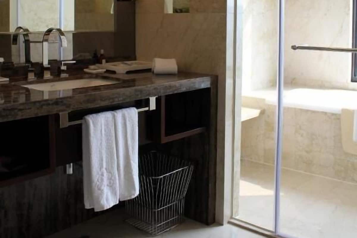 Un baño moderno con un espejo grande, una bañera y un box de ducha de cristal.