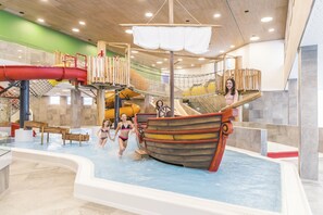 An indoor water play area with a ship-shaped slide and various climbing structures.