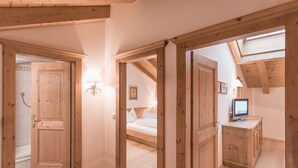 A room with wooden floors, a bed, a TV, and a cabinet.
