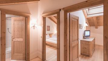A room with wooden floors, a bed, a TV, and a cabinet.
