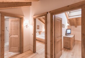 A room with wooden floors, a bed, a TV, and a cabinet.
