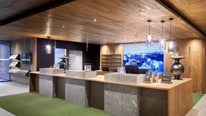 A reception desk with a wooden ceiling, a large screen displaying a snowy mountain landscape, and a green carpeted floor.