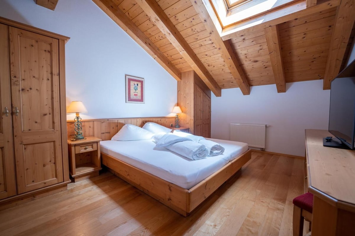 Une chambre à coucher avec un lit en bois, deux tables de chevet avec des lampes, un radiateur et une armoire en bois.
