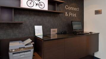A reception desk with a printer, a computer monitor, and a sign that reads "Connect & Print."