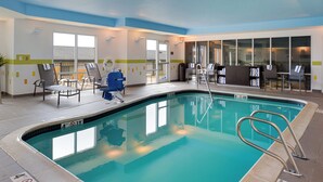 An indoor swimming pool with clear water, a lifeguard chair, and a lounge area with chairs and a table. - Fairfield Inn & Suites Cedar Rapids (Cedar Rapids)