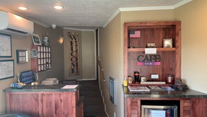 A reception area with a wooden desk, a 'Welcome' sign, a 'Cafe' sign, a refrigerator with beverages, and a 'Dog' sign. - Oregon Trail Inn (Buhl)