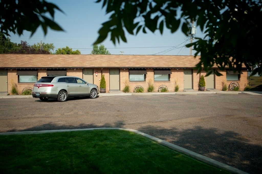 A motel with a row of rooms, a parking lot, and a car parked in front.
