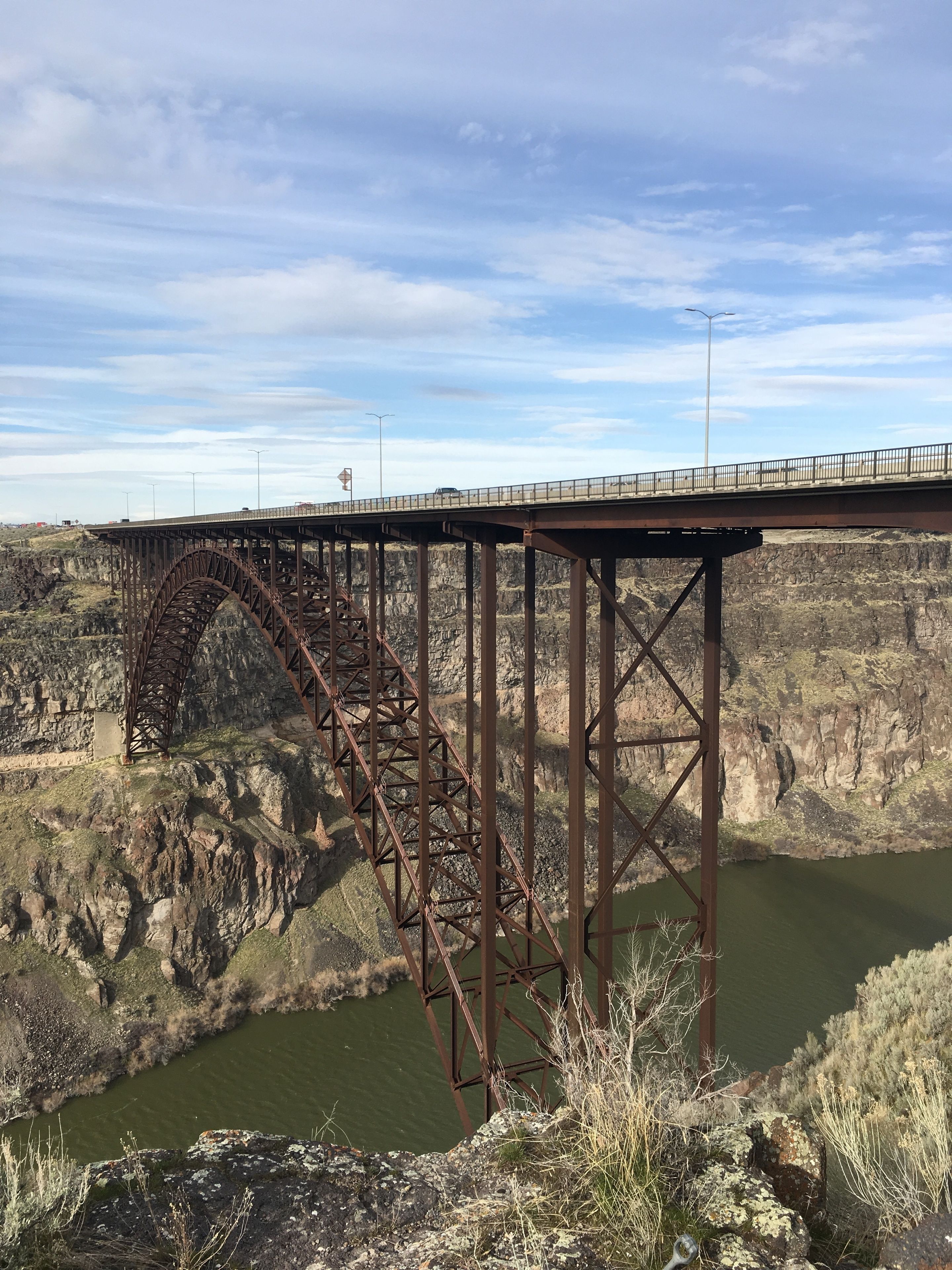 Un gran puente metálico que cruza un profundo cañón con un río debajo.