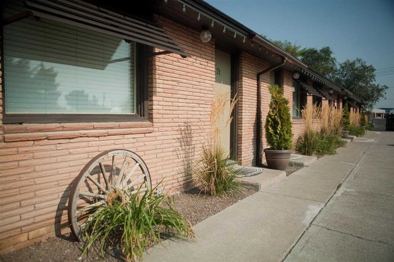 A row of brick buildings with large windows and a vintage wagon wheel.