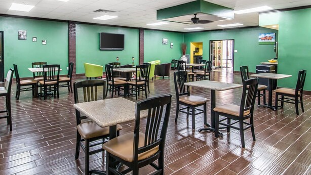 A restaurant with green walls, tiled flooring, and multiple tables and chairs.