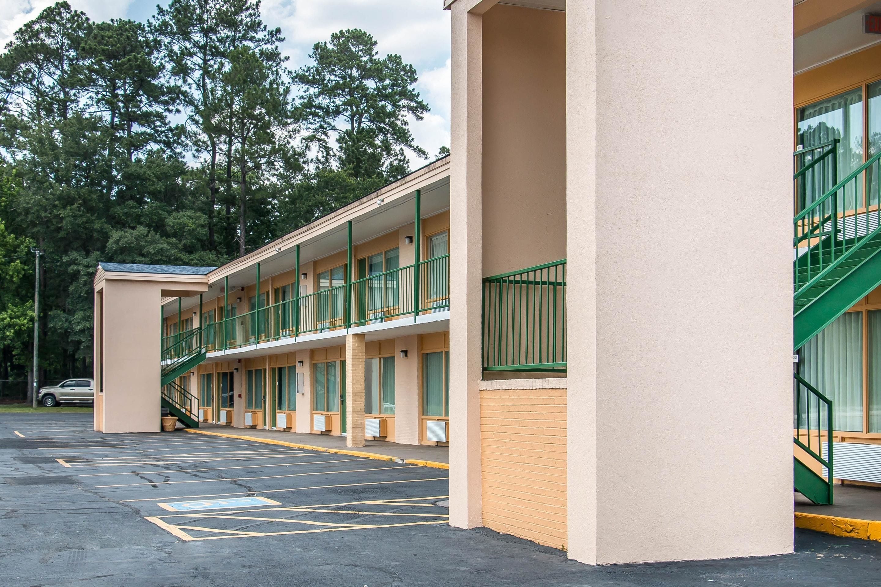 A motel with a two-story structure, a covered parking area, and a staircase leading to the upper level.