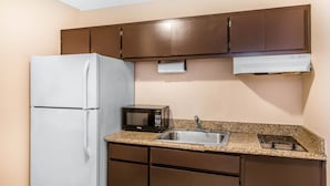 A compact kitchen with a refrigerator, microwave, sink, and a built-in oven.