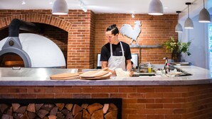 Uma estação de pizza ao forno de tijolos, com um chef preparando a massa.