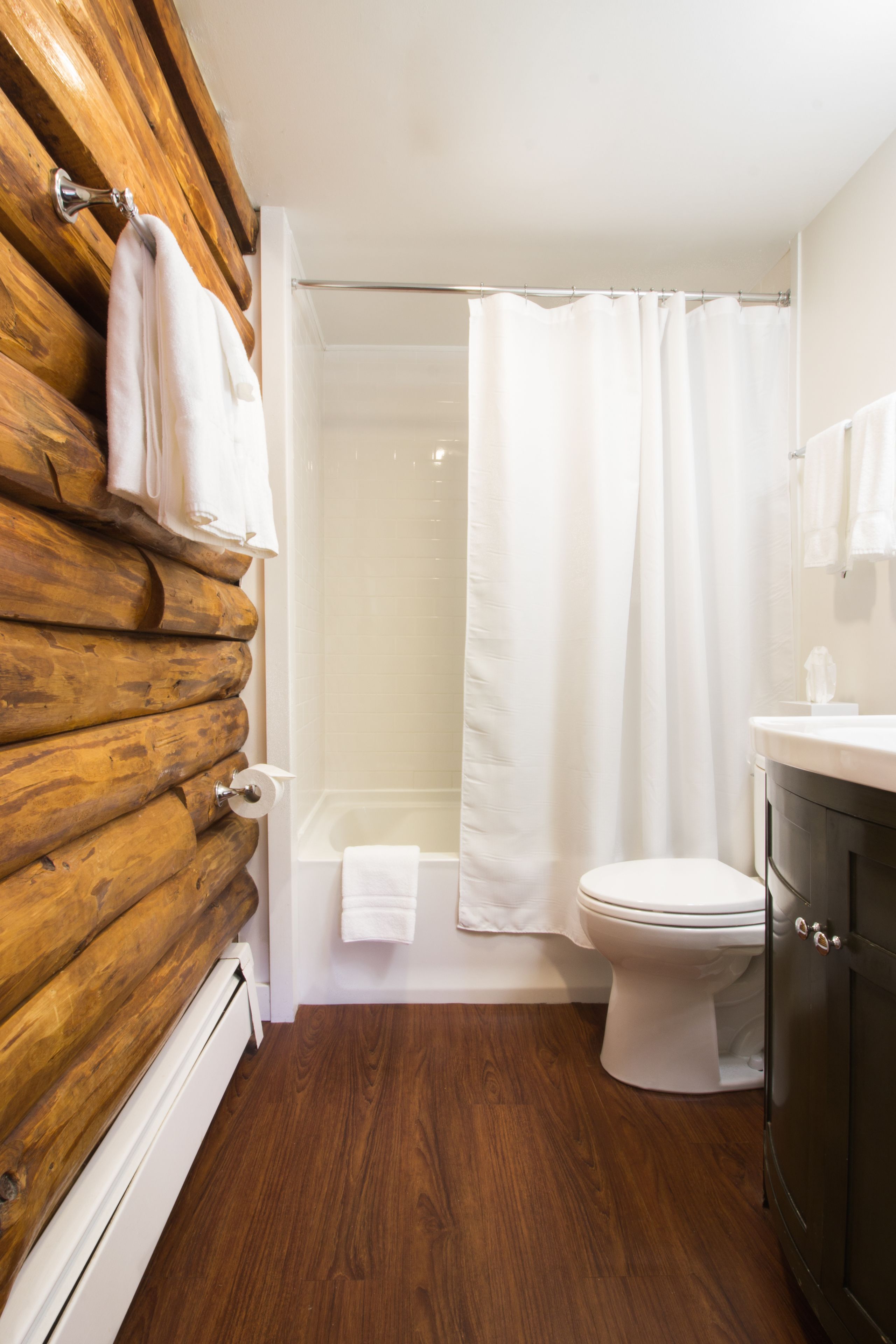 A bathroom with a wooden wall, a bathtub, a toilet, and a shower curtain.