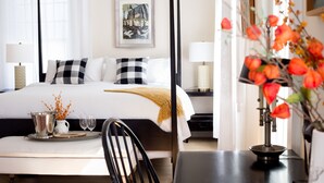 Quarto de hotel com uma cama grande, mesas de cabeceira, uma escrivaninha e uma cadeira.