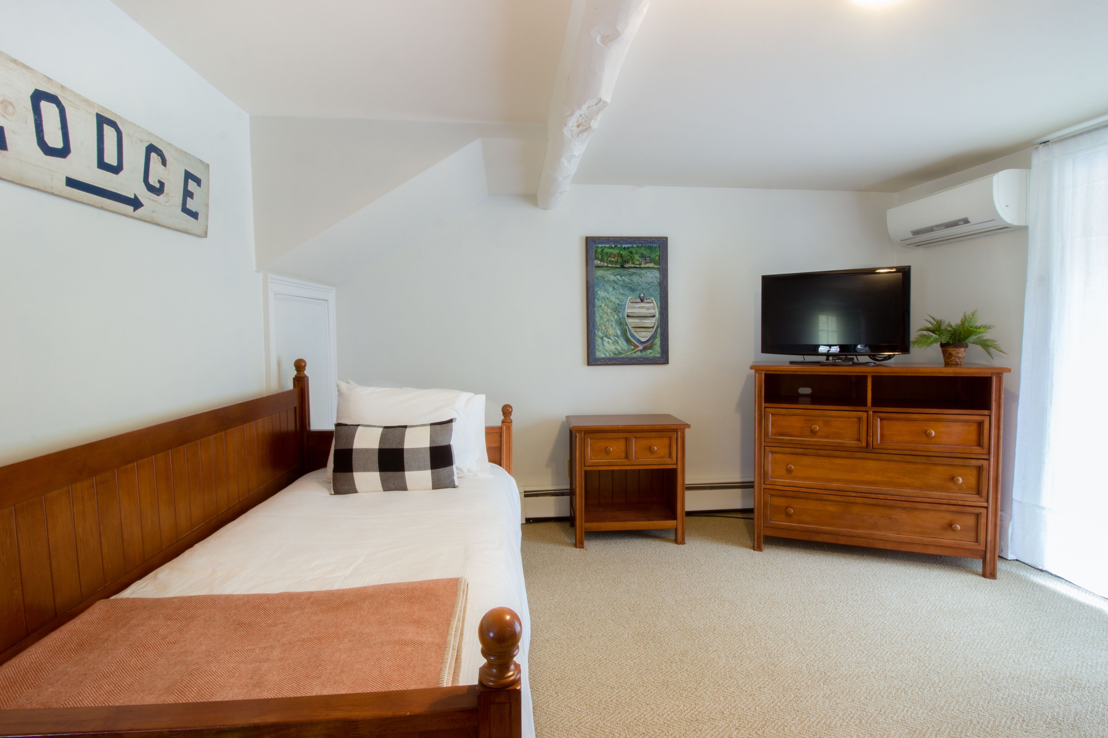 A bedroom with a bed, a dresser, a television, and a painting on the wall.