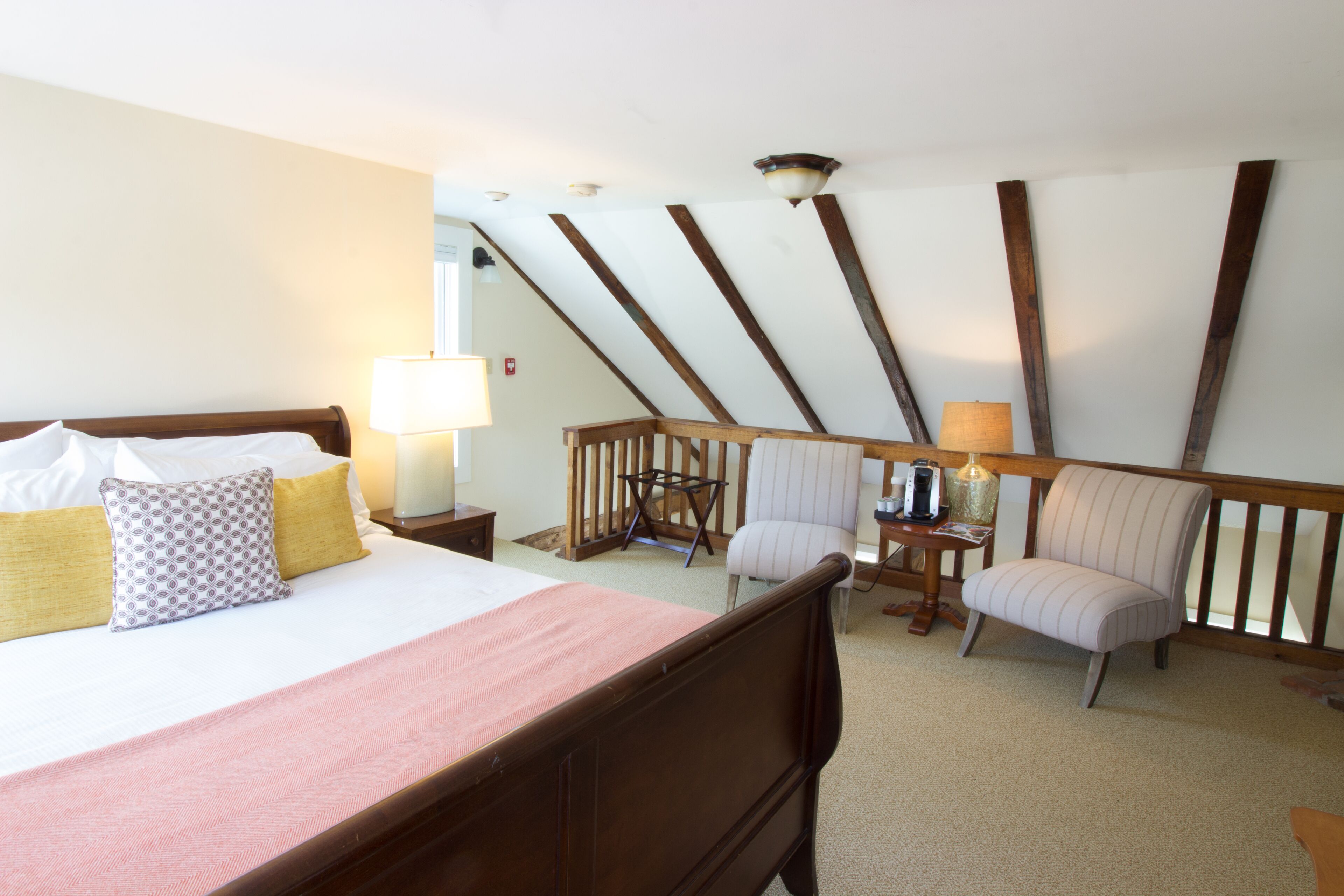 Une chambre d’hôtel avec un grand lit, une chaise, une petite table et une lampe.