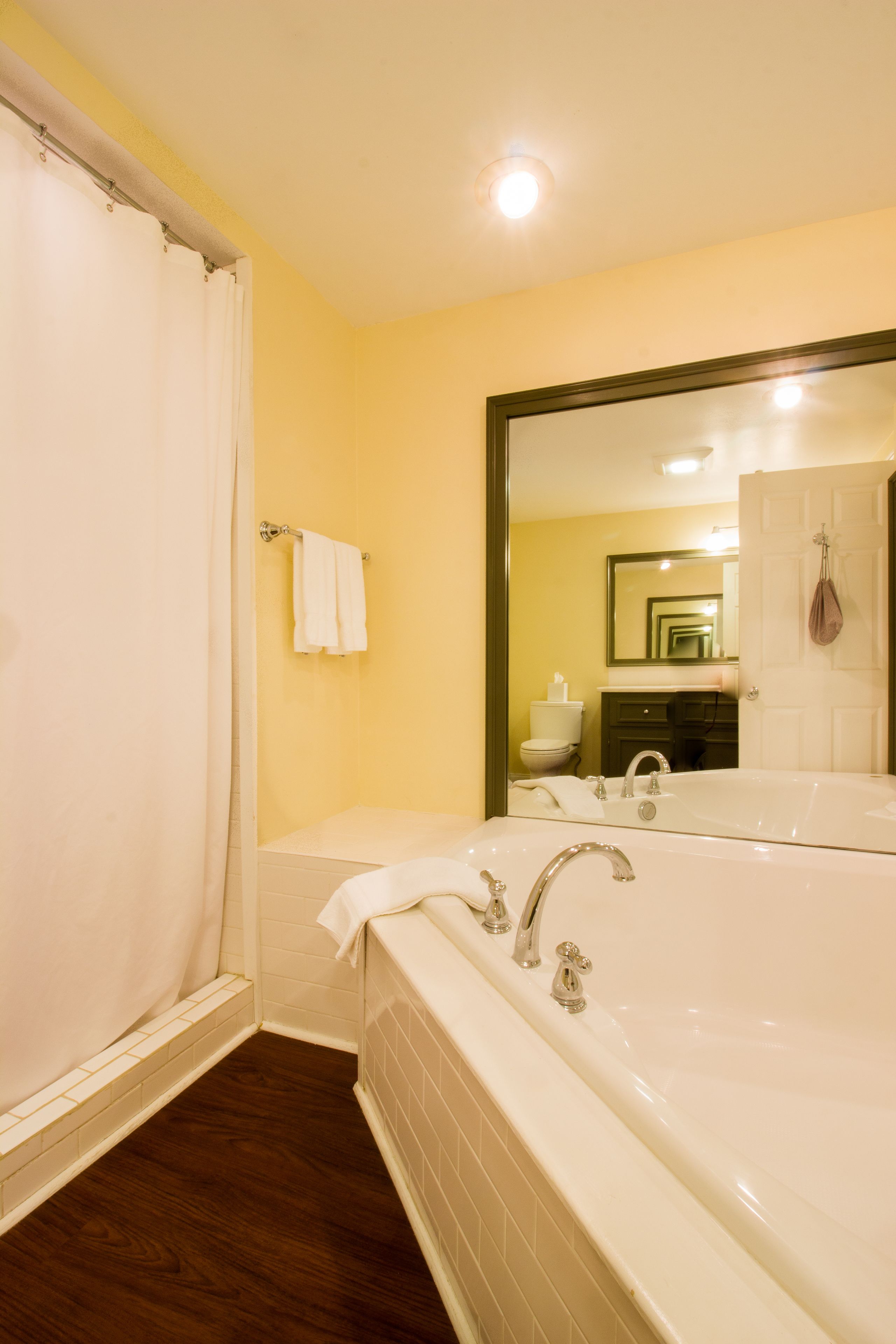 A bathroom with a bathtub, a shower curtain, a toilet, and a sink.