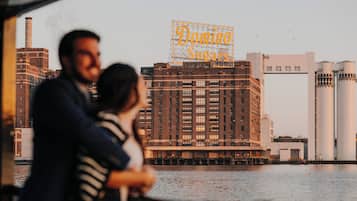 Ett par står och blickar ut över en stadsbild med industriella byggnader och en tydlig skylt med texten ”Domino Sugars”.