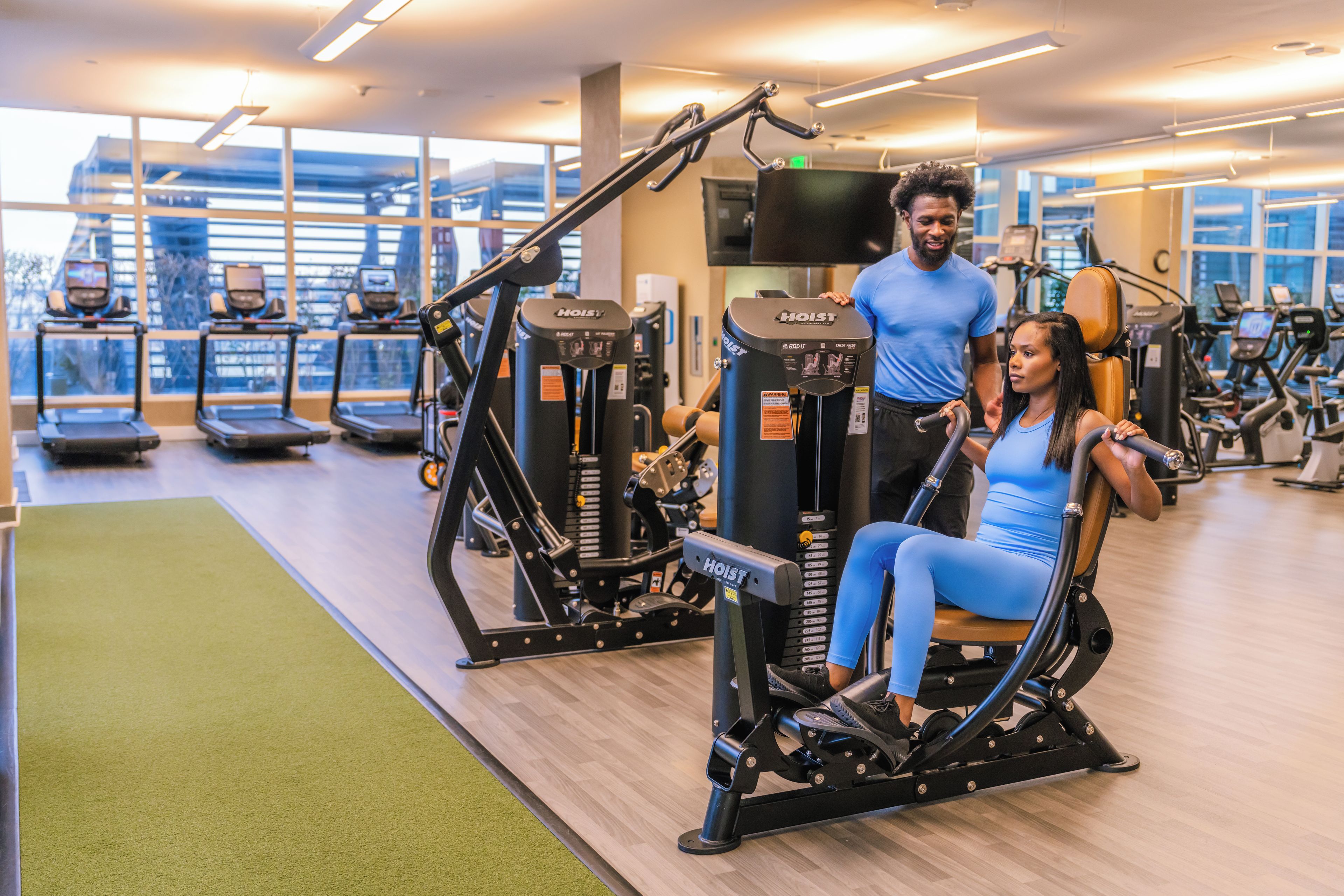 A gym with exercise equipment, treadmills, and a green mat area.