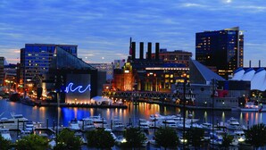A marina with boats docked, a bridge, and buildings with illuminated windows. - Four Seasons Hotel Baltimore (Baltimore)