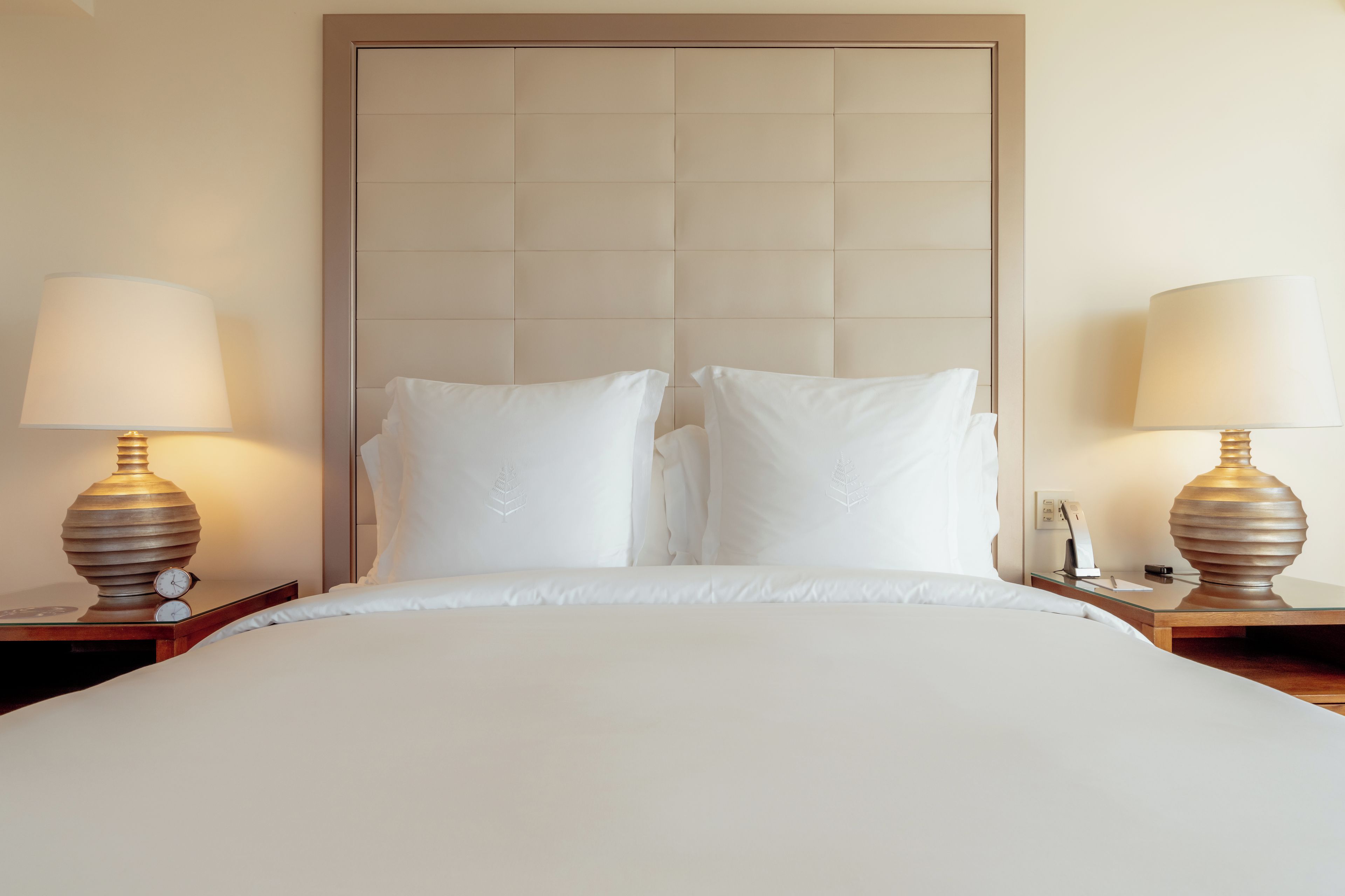 A hotel room with a large bed, two bedside tables, and two lamps.