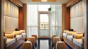 Une salle de spa dotée de sièges confortables, d’une porte vitrée donnant sur l’extérieur et d’un luminaire au plafond.