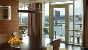 Un comedor moderno con una mesa grande, sillas y vistas a un paisaje urbano a través de amplios ventanales.