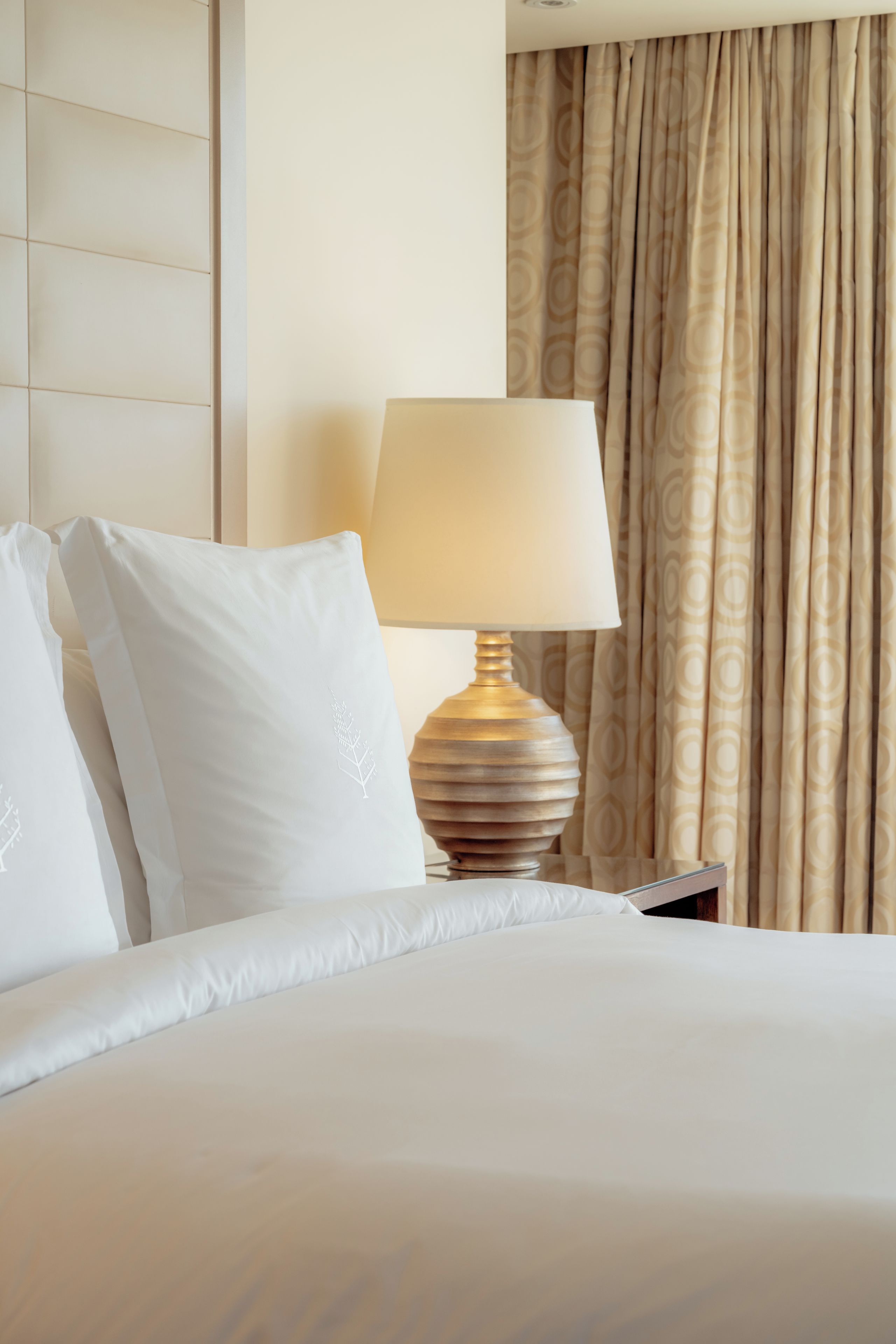 Une chambre d’hôtel avec un lit, une lampe de chevet et un rideau.