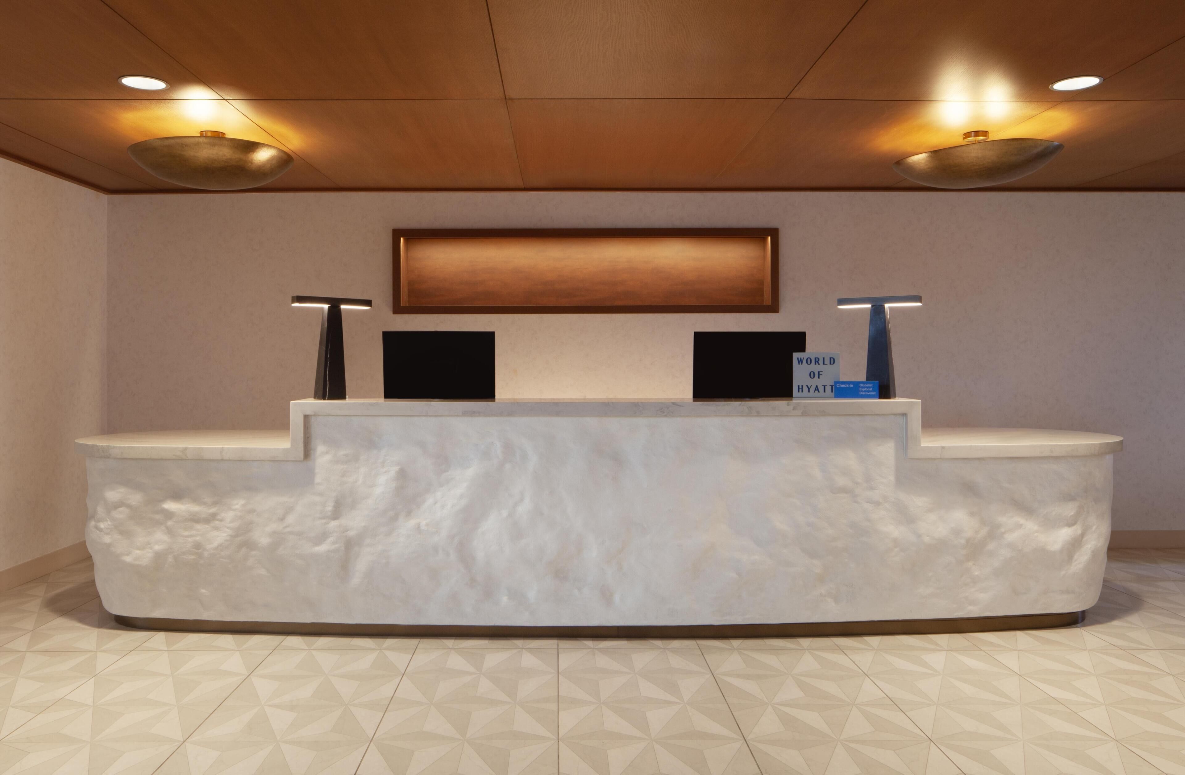 A reception desk with a marble top, two black speakers, and a blue sign.