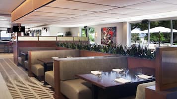 A restaurant with booth seating, a patterned floor, and a view of the outdoors.