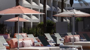 Una piscina al aire libre, camas de piscina con cargo, sombrillas