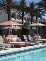 Una piscina al aire libre, camas de piscina con cargo, sombrillas