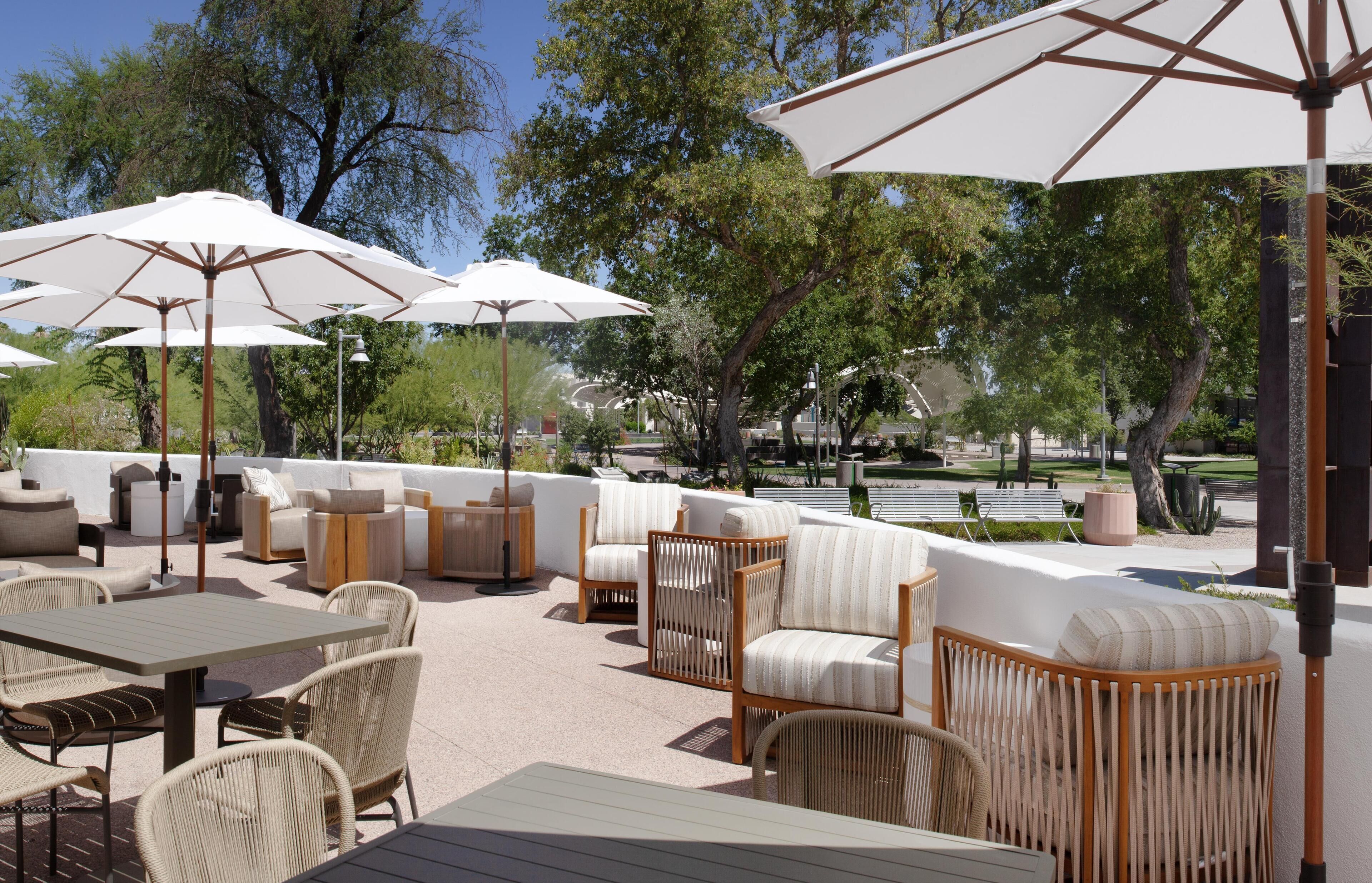 An outdoor seating area with tables, chairs, and umbrellas.