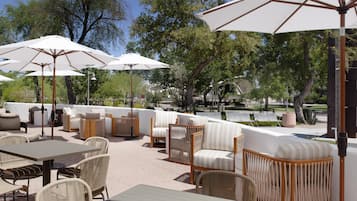 An outdoor seating area with tables, chairs, and umbrellas.