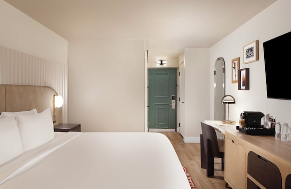 Una habitación de hotel con cama, mesita de noche, escritorio, silla y televisor.